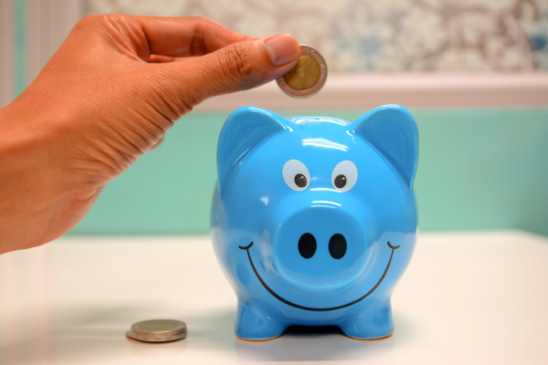 Person putting savings into piggy bank.